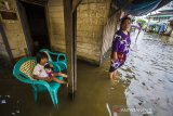 Warga berdiri di depan rumahnya yang terendam banjir akibat luapan Sungai Martapura di Kelayan A, Banjarmasin, Kalimantan Selatan, Senin (5/4/2021). Hujan deras yang mengguyur sejumlah wilayah di Provinsi Kalimantan Selatan beberapa hari belakangan ini membuat kanal dan Sungai Martapura di Kota Banjarmasin meluap sehingga mengakibatkan sejumlah rumah dan jalan terendam banjir. Foto Antaranews Kalsel/Bayu Pratama S.