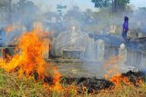 Warga berjalan di areal sekitar makam yang terbakar saat pelaksanaan tradisi ceng beng (ziarah kubur) di Jambi, Minggu (4/4/2021). Kebakaran lahan di sekitar makam saat Kota Jambi memasuki musim kemarau itu dipicu abu uang-uangan kertas sisa ritual yang terbang terbawa angin. ANTARA FOTO/Wahdi Septiawan/foc..