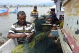 Nelayan memperbaiki jaring saat cuaca buruk di Pelabuhan Panarukan, Situbondo, Jawa Timur, Kamis (8/4/2021). Sejumlah nelayan tidak melaut selama cuaca buruk dan mengisi waktu dengan memperbaiki jaring, membersihkan jaring sambil menunggu cuaca baik. Antara Jatim/Seno/zk
