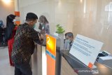 PENERAPAN QANUN LEMBAGA KEUANGAN SYARIAH DI ACEH. Karyawan bank melayani nasabah saat melakukan transaksi keuangan di kantor cabang BNI Syariah Indonesia, Banda Aceh, Aceh, Kamis (8/4/2021). Penerapan Qanun (peraturan daerah) Lembaga Keuangan Syariah di Aceh mewajibkan semua perbankan di daerah itu harus memiliki Unit Syariah dan terhitung Juni 2021 beberapa bank konvensional yang tidak memiliki Unit Syariah akan tutup beroperasi meninggalkan di Aceh. ANTARA FOTO/Ampelsa.