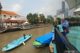 Warga mengamati perahu wisata yang melintas di Sungai Kalimas di Taman Prestasi Jalan Ketabang Kali, Surabaya, Jawa Timur, Sabtu (10/4/2021). Pemkot Surabaya membuka kembali delapan taman kota di Surabaya yang sebelumnya ditutup karena pandemi COVID-19 dengan menerapkan pembatasan jumlah pengunjung dan protokol kesehatan ketat. Antara Jatim/Didik Suhartono/zk.