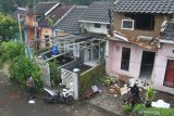 Seorang warga melintas di depan rumah yang rusak akibat gempa di Majangtengah, Malang, Jawa Timur, Minggu (11/4/2021). Badan Nasional Penanggulangan Bencana (BNPB) melaporkan sedikitnya 1.189 unit rumah rusak akibat gempa bermagnitudo 6,1 yang mengguncang kawasan Malang dan sekitarnya. Antara Jatim/Ari Bowo Sucipto/zk.