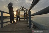 Sejumlah warga bersantai menunggu waktu berbuka puasa (ngabuburit) di Pantai Rembat, Juntinyuat, Indramayu, Jawa Barat, Selasa (13/4/2021). Pantai Rembat yang berada di Pantai Utara Jawa itu menjadi salah satu lokasi favorit warga saat bulan Ramadhan untuk menunggu waktu berbuka puasa sambil menikmati terbenamnya matahari. ANTARA JABAR/Dedhez Anggara/agr