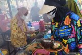 Penjual makanan melayani pembeli di Pasar Pundensari desa wisata Gunungsari, Kabupaten Madiun, Jawa Timur, Minggu (11/4/2021). Pasar Pundensari menjadi destinasi wisata bagi masyarakat Madiun dan sekitar yang ingin menikmati suasana pedesaan dengan makanan dan minuman yang disajikan secara tradisional dan unik, misalnya transaksi pembayaan dilakukan menggunakan bilah bambu sebagai pengganti uang. Antara Jatim/Siswowidodo/zk.