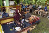 Seniman memainkan seni tradisional cokekan untuk menghibur pengunjung saat hari ulang tahun kedua Pasar Pundensari di desa wisata Gunungsari, Kabupaten Madiun, Jawa Timur, Minggu (11/4/2021). Pasar Pundensari menjadi destinasi wisata bagi masyarakat Madiun dan sekitar yang ingin menikmati suasana pedesaan dengan makanan dan minuman yang disajikan secara tradisional dan unik, misalnya transaksi pembayaan dilakukan menggunakan bilah bambu sebagai pengganti uang. Antara Jatim/Siswowidodo/zk.