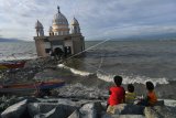 Warga menunggu datangnya waktu berbuka puasa (ngabuburit) di sekitar Masjid Terapung Arkam Babu Rahman yang rusak akibat diterjang tsunami di Pantai Teluk Palu di Palu, Sulawesi Tengah, Selasa (13/4/2021). Pantai Teluk Palu menjadi salah satu tempat ngabuburit masyarakat setempat di bulan Ramadhan sembari menikmati pemandangan sore. ANTARA FOTO/Mohamad Hamzah/foc.