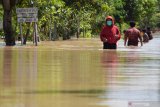  Sejumlah warga menerobos jalan yang terendam banjir di Desa Jerukgulung, Balerejo, Kabupaten Madiun, Jawa Timur, Kamis (15/4/2021). Sejumlah desa di empat kecamatan di Kabupaten Madiun terendam banjir luapan Sungai Jeroan akibat hujan deras Rabu (14/4) sore hingga malam. Antara Jatim/Siswowidodo/zk