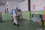 Seorang anggota Polres Madiun menyemprotkan cairan disinfektan di Masjid Baitul Rahman Desa Pagotan, Geger, Kabupaten Madiun, Jawa Timur, Selasa (20/4/2021). Kabupaten Madiun termasuk salah satu daerah yang melakukan perpanjangan Pemberlakuan Pembatasan Kegiatan Masyarakat (PPKM) berbasis Mikro untuk pengendalian penyebaran COVID-19 mulai 20 April hingga 3 Mei 2021. Antara Jatim/Siswowidodo/zk.