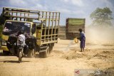 Seorang warga menyiram ruas jalan Gubernur Syarkawi yang berdebu di Kabupaten Banjar, Kalimantan Selatan, Kamis (22/4/2021). Pasca bencana alam banjir, ruas jalan nasional yang menghubungkan Provinsi Kalimantan Selatan dengan Provinsi Kalimantan Tengah itu masih mengalami kerusakan sehingga berpotensi menghambat distribusi barang di saat meningkatnya kebutuhan masyarakat jelang lebaran. Foto Antaranews Kalsel/Bayu Pratama S.