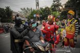 Anggota komunitas Badut Necis mengenakan masker kepada pengendara di Jalan Aruman, CImahi, Jawa Barat, Jumat (23/4/2021). Komunitas Badut Necis membagikan 100 paket takjil dan masker secara gratis kepada warga sebagai bentuk kepedulian terhadap sesama di Bulan Suci Ramadan. ANTARA JABAR/Raisan Al Farisi/agr