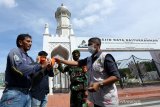 Tim Satuan tugas (Satgas) gabungan COVID-19 Kota Banda Aceh memberikan masker kepada warga yang telah menjalani hukuman sosial saat terjaring razia protokol kesehatan (prokes) di depan Masjid Raya Baiturrahman, Banda Aceh, Aceh, Jumat (30/4/2021). Razia prokes yang dilaksanakan tim Satgas untuk mencegah dan meminimalkan lonjakan kasus COVID-19 yang terjadi akibat ketidakpatuhan masyarakat terhadap prokes yang dianjurkan Pemerintah. Antara Aceh/Irwansyah Putra.