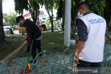 Tim Satuan tugas (Satgas) gabungan COVID-19 Kota Banda Aceh mengawasi warga yang sedang menjalani hukuman sosial menyapu taman saat terjaring razia protokol kesehatan (prokes) di depan Masjid Raya Baiturrahman, Banda Aceh, Aceh, Jumat (30/4/2021). Razia prokes yang dilaksanakan tim Satgas untuk mencegah dan meminimalkan lonjakan kasus COVID-19 yang terjadi akibat ketidakpatuhan masyarakat terhadap prokes yang dianjurkan Pemerintah. Antara Aceh/Irwansyah Putra.