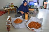 PERMINTAAN BAWANG GORENG HOME INDUSTRI. Pekerja memasukan bawang goreng ke dalam kemasan plastik  di salah satu home industri, Desa Lampeunerut, kecamatan Darul Imara, Kabupaten Aceh Besar, Aceh, Sabtu (1/5/2021). Pelaku usaha menyatakan produksi bawang goreng tidak terdampak pandemi COVID-19 dan menjelang hari raya Idul Fitri permintaan produk bawang goreng meningkat kisaran 75 persen  dengan harga penjualan Rp40.000 hingga Rp58.000 per bungkus menurut ukurannya. ANTARA FOTO/Ampelsa.