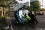 Petugas bahu-membahu membalikkan taksi Bluebird yang terbalik di Jalan A Yani, Surabaya, Jawa Timur, Senin (3/5/2021). Taxi Bluebird yang bernomor lambung WE 832 dengan nomor polisi L 1732 UO tersebut diduga mengalami kecelakaan tunggal saat melintas di jalan tersebut dan pengemudinya dilarikan ke rumah sakit untuk menjalani perawatan. Antara Jatim/Didik Suhartono/zk.