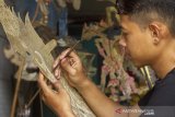 Perajin menyelesaikan pembuatan kerajinan wayang kulit di workshop Panurat Jagat, Desa Banyuasih, Banyusari, Karawang, Jawa Barat, Senin (3/5/2021). Kerajinan wayang kulit yang dibuat dari bahan dasar kulit kerbau dan kulit sapi tersebut dijual dengan harga Rp500 ribu - Rp3 juta tergantung bahan kulit, karakter dan tingkat kesulitan. ANTARA JABAR/M Ibnu Chazar/agr