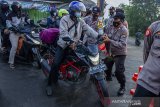 Petugas gabungan menghalau pemudik yang melintas di perbatasan Karawang-Bekasi, Jawa Barat, Minggu (9/5/2021). Korlantas Polri mencatat selama tiga hari dari 381 titik penyekatan larangan mudik, polisi telah memutarbalikkan sekitar 70 ribu lebih kendaraan yang tidak memenuhi persyaratan perjalanan atau terindikasi mudik. ANTARA JABAR/M Ibnu Chazar/agr