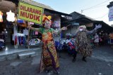 Anggota polisi yang mengenakan kostum 'celuluk' atau sosok menyeramkan bersama seniman lokal Bali melakukan atraksi kesenian saat edukasi larangan mudik di Pasar Taman Sari Merta Kerobokan, Badung, Bali, Selasa (11/5/2021). Kegiatan tersebut digelar untuk mengingatkan masyarakat mengenai larangan mudik Hari Raya Idul Fitri 1442 Hijriah menyusul masih adanya warga yang nekat mudik dengan bermacam-macam cara. ANTARA FOTO/Nyoman Hendra Wibowo/nym.