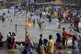 Pengunjung menikmati suasana liburan di pantai Karangsong, Indramayu, Jawa Barat, Jumat (14/5/2021). Obyek wisata pantai Karangsong ramai dikunjungi warga pada hari kedua Lebaran meskipun ada larangan membuka tempat wisata oleh Pemda setempat. ANTARA JABAR/Dedhez Anggara/agr