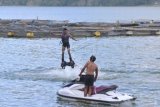 Wisatawan bermain wahana 'Flying Board' di kawasan Danau Batur, Kintamani, Bangli, Bali, Sabtu (15/5/2021). Kawasan Danau Batur menjadi salah satu destinasi pariwisata di Bali yang ramai dikunjungi oleh wisatawan lokal selama masa liburan Hari Raya Idul Fitri 1442 Hijriah. ANTARA FOTO/Fikri Yusuf/nym.