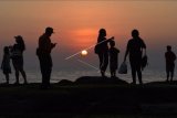 Wisatawan lokal menyaksikan matahari terbenam saat menikmati suasana hari terakhir liburan Idul Fitri di Pantai Tanah Lot, Tabanan, Bali, Minggu (16/5/2021). Kunjungan wisatawan di obyek wisata tersebut mengalami penurunan saat hari terakhir masa liburan Idul Fitri 1442 Hijriah karena aktivitas perkantoran sudah dimulai pada Senin (17/5/2021). ANTARA FOTO/Nyoman Hendra Wibowo/nym.