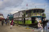 Warga melintas di dekat kapal motor Pancar Mas II Banjarmasin-Kalteng di Dermaga Banjar Raya, Banjarmasin, Kalimantan Selatan, Senin (17/5/2021). Menurut pihak pengelola kapal motor, arus balik dari Banjarmasin menuju sejumlah daerah pelosok di Kalsel-Kalteng melalui jalur sungai mulai meningkat setelah dibukanya dermaga penyeberangan pascapenutupan selama enam hari saat Lebaran. Foto Antaranews Kalsel/Bayu Pratama S.