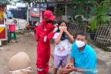 Relawan SIBAT PMI membagikan masker sambil memberi informasi tentang  Perilaku Hidup Bersih dan Sehat (PHBS) yang menjadi kewajiban dalam kehidupan sehari-hari kepada warga. (Foto Antara/HO/PMI/IFRC).