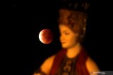 Gerhana bulan total terlihat dari balik patung penari gandrung di Watu Dodol, Banyuwangi, Jawa Timur, Rabu (26/5/2021). Fenomena gerhana bulan total yang disebut 'super blood moon' itu terjadi saat posisi matahari, bumi, dan bulan sejajar dan hanya terjadi disaat fase bulan purnama. Antara Jatim/Budi Candra Setya/zk