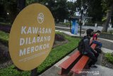 Warga duduk di area larangan merokok di Taman Balai Kota,  Bandung, Jawa Barat, Jumat (28/5/2021). Pemerintah Kota Bandung mengeluarkan  Perda Nomor 10/2021 tentang KTR (Kawasan Tanpa Rokok) antara lain fasilitas pelayanan kesehatan, tempat proses belajar mengajar, tempat bermain anak, tempat ibadah, transportasi umum, tempat kerja, tempat umum/publik dengan denda Rp500 ribu atau sanksi kerja sosial apabila warga kedapatan melanggar. ANTARA JABAR/Novrian Arbi/agr