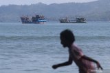 Seorang anak berlari dengan latar belakang perahu nelayan di pantai Sidem, Tulungagung, Jawa Timur, Selasa (1/6/2021). Wisata pantai Sidem yang kembali dibuka tersebut ramai pengunjung saat libur hari lahir Pancasila. Antara Jatim/Prasetia Fauzani/zk