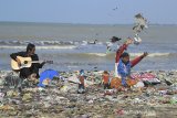 Pendongeng sekaligus seniman tutur Samsudin (kanan) melakukan aksi teatrikal dengan latar belakang tumpukan sampah plastik di pantai Dadap, Juntinyuat, Indramayu, Jawa Barat, Sabtu (6/5/2021). Aksi teatrikal dalam rangka memperingati hari Lingkungan Hidup Sedunia itu untuk mengkritisi pengelolaan sampah plastik di Indonesia. ANTARA JABAR/Dedhez Anggara/agr