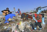 Pendongeng sekaligus seniman tutur Samsudin (kanan) melakukan aksi teatrikal dengan latar belakang tumpukan sampah plastik di pantai Dadap, Juntinyuat, Indramayu, Jawa Barat, Sabtu (6/5/2021). Aksi teatrikal dalam rangka memperingati hari Lingkungan Hidup Sedunia itu untuk mengkritisi pengelolaan sampah plastik di Indonesia. ANTARA JABAR/Dedhez Anggara/agr