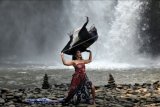 Model menampilkan rancangan kain tradisional atau wastra nusantara yang diperagakan di area air terjun Tegenungan, Gianyar, Bali, Sabtu (5/6/2021). Peragaan wastra nusantara dengan konsep budaya dipadukan dengan alam tersebut untuk memperingati Hari Lingkungan Hidup Sedunia sekaligus melestarikan kain tradisional yang sarat akan makna budaya nusantara. ANTARA FOTO/Nyoman Hendra Wibowo/nym.