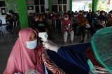 Petugas memeriksa suhu tubuh warga sebelum mendapat suntikan vaksin COVID-19 AstraZeneca saat vaksinasi bagi warga lanjut usia (lansia) dan pedagang pasar di balai Kelurahan Nambangan Lor, Kota Madiun, Jawa Timur, Rabu (9/6/2021). Vaksinasi bagi warga lansia dan pedagang pasar tersebut dimaksudkan untuk percepatan vaksinasi bagi warga guna penanggulangan penyebaran COVID-19. Antara Jatim/Siswowidodo/zk