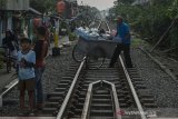 Pedagang melintasi rel kawasan pemukiman jalur kereta api Kiaracondong, Bandung, Jawa Barat, Kamis (10/6/2021). Kementerian Perhubungan dan Pemerintah Kota Bandung berencana melanjutkan pembangunan tahap II rel ganda atau double track sepanjang 26 km  jalur Kereta Api Kiaracondong-Cicalengka dengan merelokasi sedikitnya 900 bidang tanah dan bangunan di kawasan tersebut sekaligus penunjang jalur Kereta Cepat Jakarta-Bandung. ANTARA JABAR/Novrian Arbi/agr