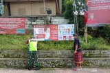 Relawan Palang Merah Indonesia (PMI) dibantu TNI/Polri memasang spanduk untuk mendukung upaya diseminasi informasi terkait COVID-19 kepada warga. (Antara/HO/PMI/IFRC).