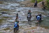 Pengendera sepeda motor menyeberangi di Sungai Sintok yang dangkal di Desa Ciparakan, Kecamatan Kalipucang, Kabupaten Pangandaran, Jawa Barat, Jumat (18/6/2021). Akibat tidak ada jembatan selama puluhan tahun, warga di Kecamatan Kalipucang, Sidamulih dan Padaherang, terpaksa harus menyeberangi sungai untuk melakukan aktivitas dan jika debit air sungai naik atau meluap aktivitas warga terganggu karena tidak bisa dilalui. ANTARA FOTO/Adeng Bustomi/agr