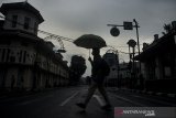 Siluet warga melintasi jalan saat penutupan ruas jalan protokol kawasan Asia Afrika, Bandung, Jawa Barat, Jumat (18/6/2021). Pemerintah Kota Bandung kembali melakukan penutupan ruas jalan protokol dan jalur perbatasan bagi kendaraan pada pukul 14.00 WIB hingga 16.00 dan 18.00 WIB hingga 05.00 WIB guna menekan penyebaran COVID-19 terkait peningkatan kasus aktif dan status siaga satu kawasan Bandung Raya. ANTARA FOTO/Novrian Arbi/agr