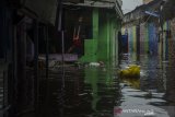 Seorang anak berdiri di atas pagar rumah yang terdampak banjir di kawasan Kacapiring, Bandung, Jawa Barat, Senin (21/6/2021). Puluhan rumah di kawasan tersebut terendam banjir setinggi 30 cm hingga dua meter akibat intensitas curah hujan yang tinggi dan luapan Sungai Cikudapateuh Dalam. ANTARA FOTO/Novrian Arbi/agr