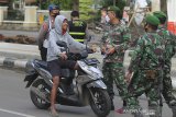 Petugas gabungan TNI/Polri menghentikan pengendara motor yang tidak menggunakan masker saat razia di Indramayu, Jawa Barat, Kamis (24/6/2021). Razia masker tersebut digelar untuk meningkatkan kesadaran masyarakat untuk tetap menerapkan protokol kesehatan sebagai upaya pencegahan penyebaran COVID-19. ANTARA FOTO/Dedhez Anggara/agr