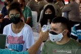 Seorang petugas mengukur suhu badan warga saat vaksinasi COVID-19 massal di Lapangan Merdeka, Kota Ambon, Provinsi Maluku, Sabtu (26/6/2021). (ANTARA FOTO/FB Anggoro)