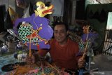 Perajin memperlihatkan wayang kulit karyanya di Desa Dukuhdempok, Wuluhan, Jember, Jawa Timur, Jumat (25/6/2021). Kerajinan wayang tersebut dijual mulai Rp25.000 - Rp250.000 per buah yang dipasarkan untuk kolektor dan anak-anak yang belajar wayang. Antara Jatim/Seno/zk