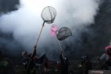 Warga menunggu sesaji yang dilemparkan ke kawah pada upacara ritual Yadnya Kasada di Kawasan Gunung Bromo, Probolinggo, Jawa Timur, Sabtu (26/6/2021). Warga tersebut berebut persembahan yang dilarung oleh masyarakt Suku Tengger saat ritual Yadnya Kasada. Antara Jatim/Budi Candra Setya/zk