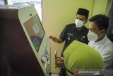 Bupati Kabupaten Bandung Dadang Supriatna (kiri) menerima penjelasan dari teknisi saat peresmian Anjungan Dukcapil Mandiri (ADM) di Kantor Desa Ciaro, Kecamatan Nagreg, Kabupaten Bandung, Jawa Barat, Rabu (30/6/2021). Pemerintah Kabupaten Bandung akan menyediakan layanan Anjungan Disdukcapil Mandiri di setiap Desa di Kabupaten Bandung guna memberikan pelayanan yang lebih mudah bagi masyarakat serta menghindari praktik pungli. ANTARA FOTO/Raisan Al Farisi/agr