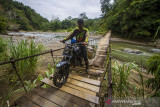 Pengendara melintas di jembatan yang rusak di Desa Datar Ajab, Kabupaten Hulu Sungai Tengah, Kalimantan Selatan, Senin (5/7/2021). Warga setempat mengeluhkan jalan penghubung antar desa yang berada di Kecamatan Hantakan tersebut masih rusak parah akibat longsor pascabanjir bandang dan hingga kini belum diperbaiki sehingga mengganggu aktivitas warga. Foto Antaranews Kalsel/Bayu Pratama S.