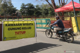 Warga melintas melalui pintu gerbang kawasan wisata gunung Kelud yang ditutup di Desa Sugihwaras, Kediri, Jawa Timur, Selasa (6/7/2021). Pemerintah daerah setempat menutup kawasan wisata gunung kelud saat penerapan Pemberlakuan Pembatasan Kegiatan Masyarakat (PPKM) Darurat guna mengendalikan penyebaran COVID-19. Antara Jatim/Prasetia Fauzani/Zk