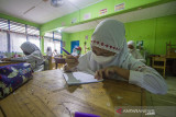 Sejumlah murid mengerjakan soal saat menjalani pembelajaran tatap muka (PTM) di SD Negeri Karang Mekar 5  Banjarmasin, Kalimantan Selatan, Senin (12/7/2021). Pemerintah Kota Banjarmasin melalui Dinas Pendidikan Kota Banjarmasin memutuskan melaksanakan PTM dengan penerapan disiplin protokol kesehatan yang ketat di tengah kenaikan kasus COVID-19. Foto Antaranews Kalsel/Bayu Pratama S.