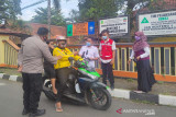 Relawan PMI, petugas kepolisian dan aparat Kelurahan Benteng, memberikan edukasi untuk kurangi mobilitas dan pentingnya penggunaan masker kepada pengandara sepeda motor  di depan SDN Benteng 1, Kecamatan Warudoyong, Kota Sukabumi, Jawa Barat. (Antara/HO/PMI/IFRC).