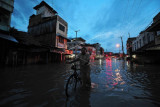 Warga menuntun sepeda saat menerobos banjir yang menggenangi Jalan Orang Kayo Hitam setelah diguyur hujan di Jambi, Senin (12/7/2021). Sejumlah ruas jalan dan permukiman warga di kota itu terendam banjir akibat buruknya sistem drainase. ANTARA FOTO/Wahdi Septiawan/wsj.