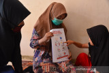GURU TK DATANGI RUMAH MURID ANTAR BUKU PELAJARAN. Guru Taman Kanak kanak Ruman Aceh (kiri) menyerahkan buku panduan bahan pelajaran kepada warga saat mendatangi kediaman murid di Desa Punge Blang Cut, Banda Aceh, Aceh, Rabu (14/7/2021). Guru TK di daerah itu mendatangi sejumlah rumah kediaman murid untuk menyerahkan bahan panduan belajar dengan dilengkapi catatan hasil karya orang tua bersama murid sebagai media alternatif pengganti belajarselama pengetatan PPKM di kota Banda Aceh berstatus zona merah,  . ANTARA FOTO/Ampelsa.