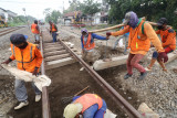  Pekerja memasang bantalan rel kereta api yang terbuat dari beton di Desa Gampengrejo, Kediri, Jawa Timur, Jumat (16/7/2021). PT Kereta Api Indonesia (Persero) secara bertahap mengganti bantalan rel yang sebelumnya menggunakan plat besi diganti menjadi beton guna meningkatkan kenyamanan dan keselamatan perjalanan kereta api. Antara Jatim/Prasetia Fauzani/zk